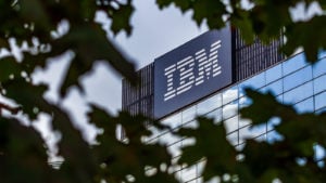 Photo of the IBM (IBM) building seen through the canopy of a tree. The IBM logo is in large letters on the side of the building.